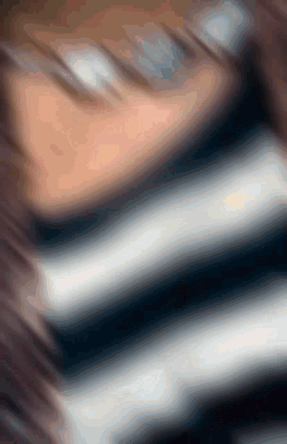 a blurry image of a person 's face with a striped shirt on