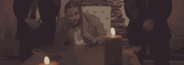 a man sitting at a table with two candles lit