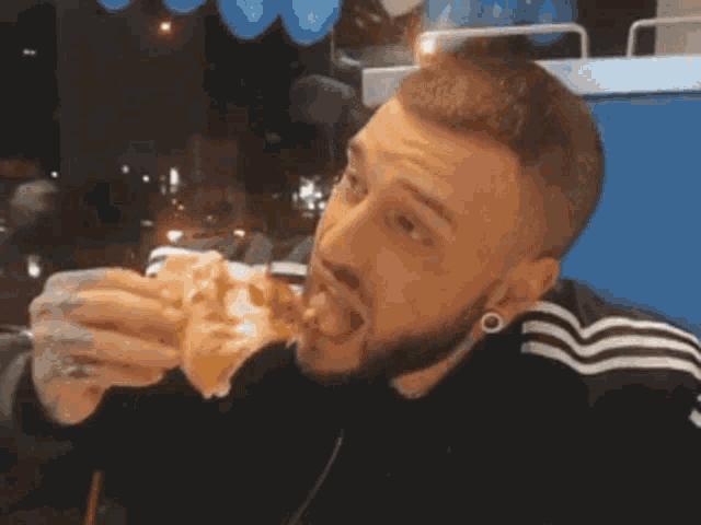 a man with a beard is eating a sandwich with his tongue hanging out