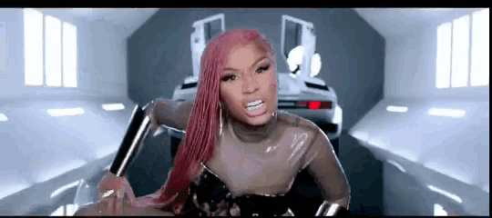 a woman with pink hair is standing in front of a car .