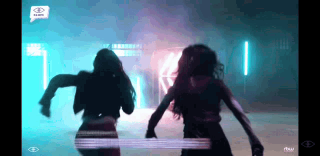 two women are dancing in front of a sign that says ' rbsw ' on it