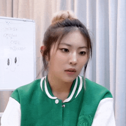 a woman wearing a green and white jacket with the letter t on it