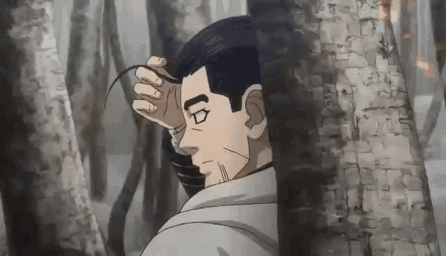 a man is peeking out from behind a tree in a forest and covering his face with his hand .