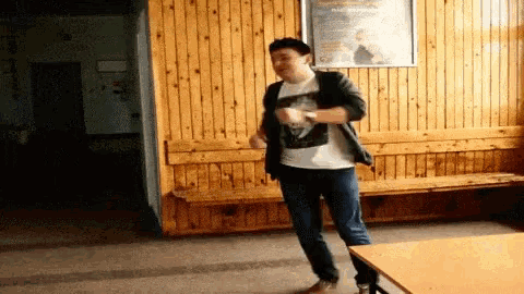 a man dancing in front of a wooden wall with a poster on it