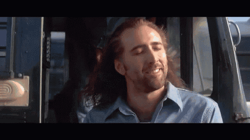 a man with long hair and a beard is smiling while sitting in a bus