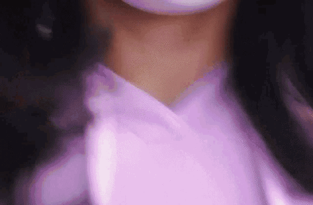 a close up of a woman wearing a purple shirt and a pink mask .