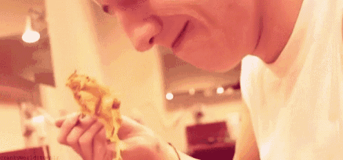 a man in a white shirt is eating a piece of cheese .