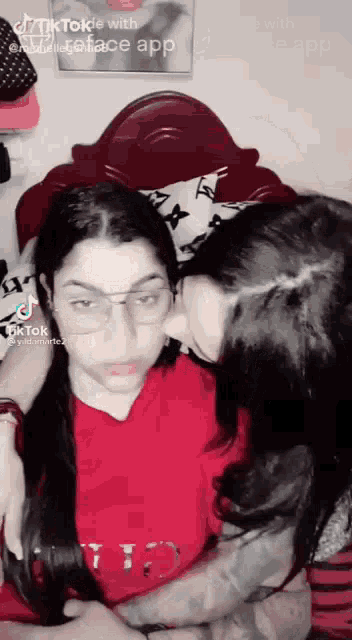 a woman is kissing another woman on the cheek while wearing glasses .