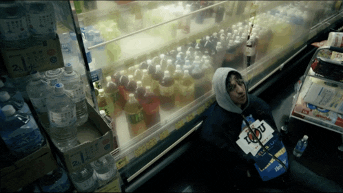 a person sitting in front of a shelf with bottles of soda