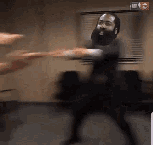 a man with a beard is dancing in front of a sign that says nba