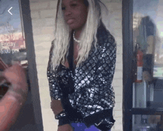 a woman wearing a sequined jacket is standing in front of a store that is open on fridays