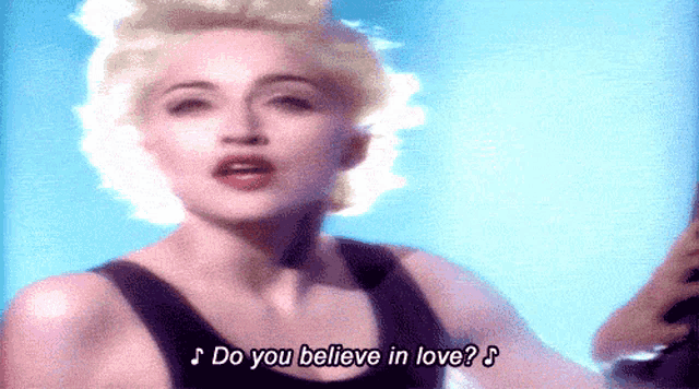 a woman in a black tank top is singing " do you believe in love "