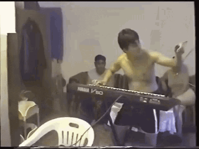 a shirtless man is playing a yamaha v60 keyboard