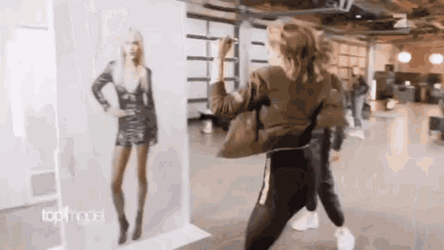 a woman is drawing a picture of a model on a wall that says topmodel on it