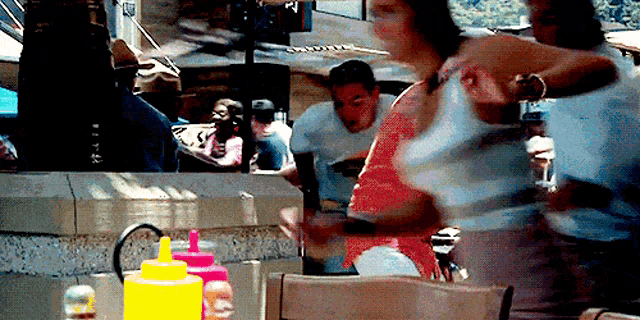 a blurry picture of people sitting at a table with bottles of ketchup and mustard in front of them