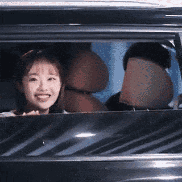 a woman is smiling while looking out of the window of a car .
