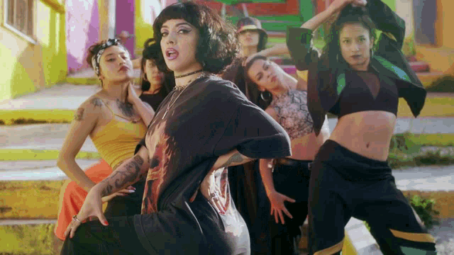 a woman in a black shirt with a tattoo on her arm is surrounded by other women