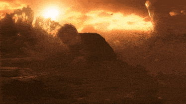 a man is laying on the ground in front of a burning building