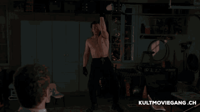 a man without a shirt in a dark room with kultmoviegang.ch written on the bottom right