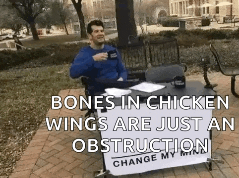 a man is sitting at a table with a sign that says bones in chicken wings are just an obstruction