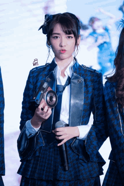a girl in a blue jacket and tie is holding a camera and microphone