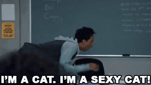 a man sitting in front of a blackboard with the words i 'm a cat