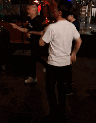a man in a white shirt is dancing in a room with other people