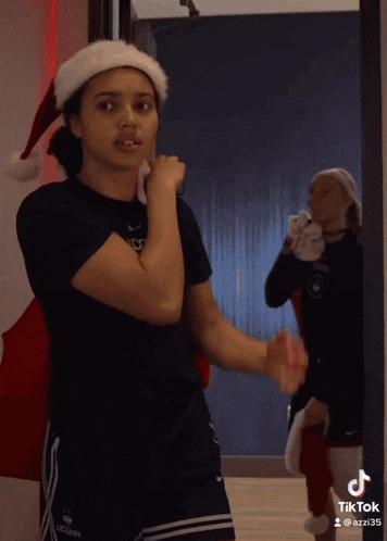 a woman wearing a white headband and a black shirt has a tiktok sticker on her shoulder
