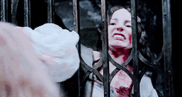a woman with blood on her face behind bars
