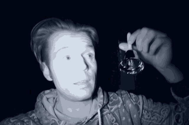 a man in a hoodie is holding a glass in his right hand