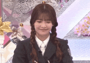 a woman in a suit and tie with braids is smiling .