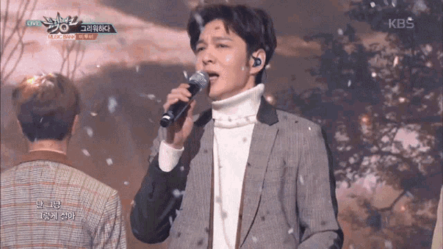 a man singing into a microphone with the kbs logo on the bottom right
