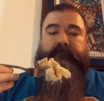 a man with a beard is eating a piece of food