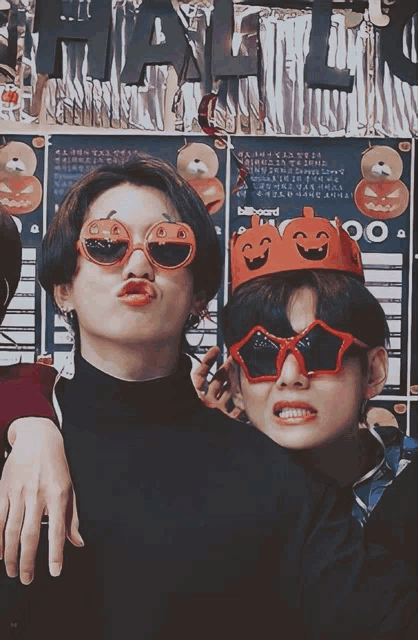 two boys wearing sunglasses and a pumpkin crown pose for a picture in front of a sign that says halloween