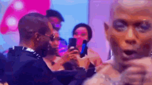 a man is talking into a microphone while a woman takes a picture of him with her cell phone .