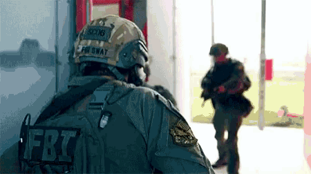 a soldier with a fbi patch on his back stands in a hallway