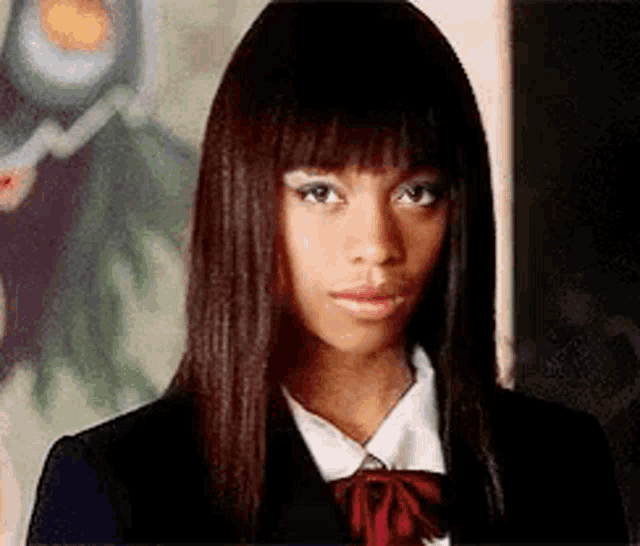 a woman with long brown hair and a red bow tie is wearing a school uniform .
