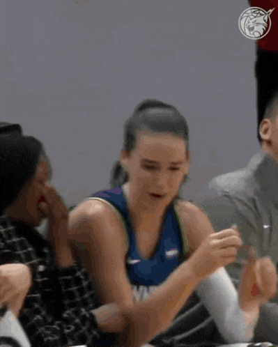 a female basketball player is giving a thumbs up while sitting in the stands