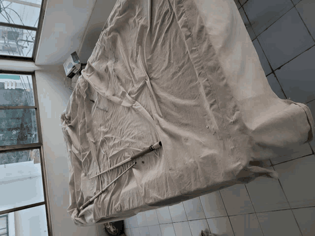 a pool table is covered in a white cloth and has a cue sticking out of it