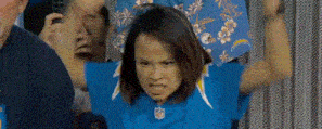 a woman wearing a blue nfl jersey is standing in front of a crowd of people .