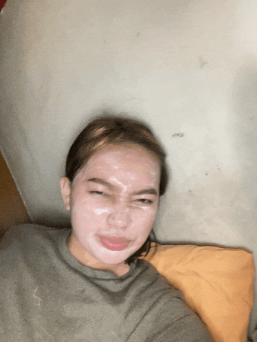 a woman with a white mask on her face laying on a bed