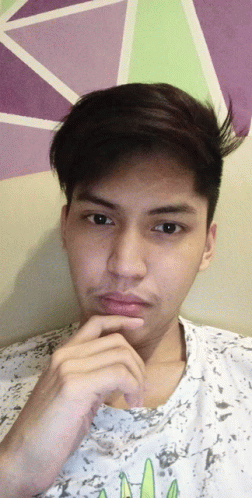 a young man with his hand on his chin wearing a white shirt with a cactus on it