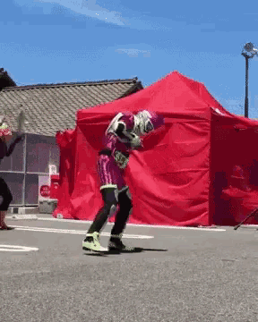 a man in a purple and green costume is walking down the street