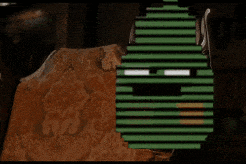 a couch with a patterned blanket and a green pixelated face on it