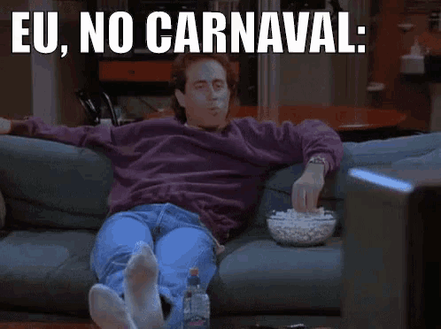 a man is sitting on a couch with a bowl of popcorn and a caption that says eu no carnaval