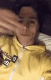 a person wearing a yellow hoodie is laying on a bed .