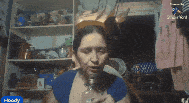 a woman is drinking from a bottle with the word hoody in the corner
