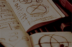 a person is drawing a circle with a cross on it in a notebook