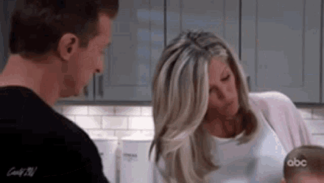 a man and woman are holding a baby in a kitchen .