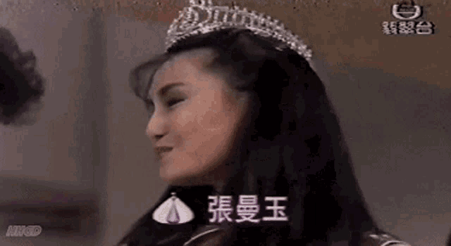 a woman wearing a tiara is smiling and waving .